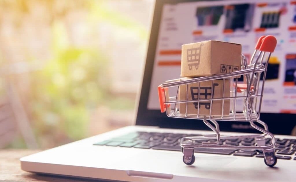 Mini shopping cart with box on laptop.