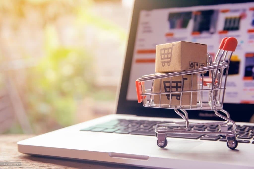 Mini shopping cart with box on laptop.