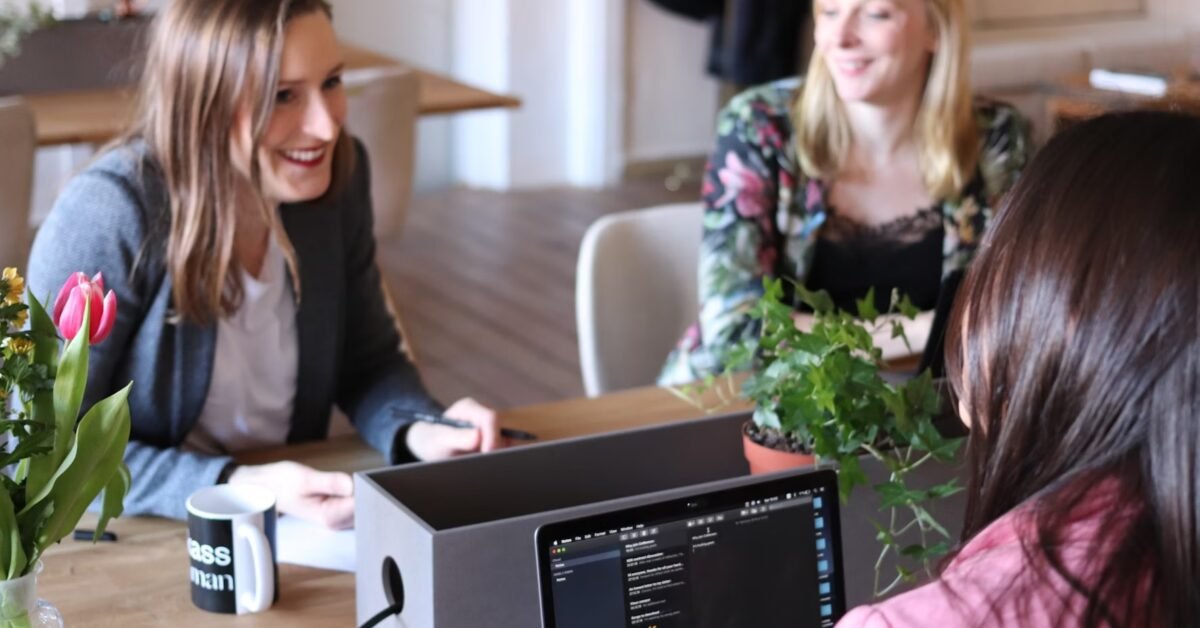 Three colleagues in an office meeting with laptop.