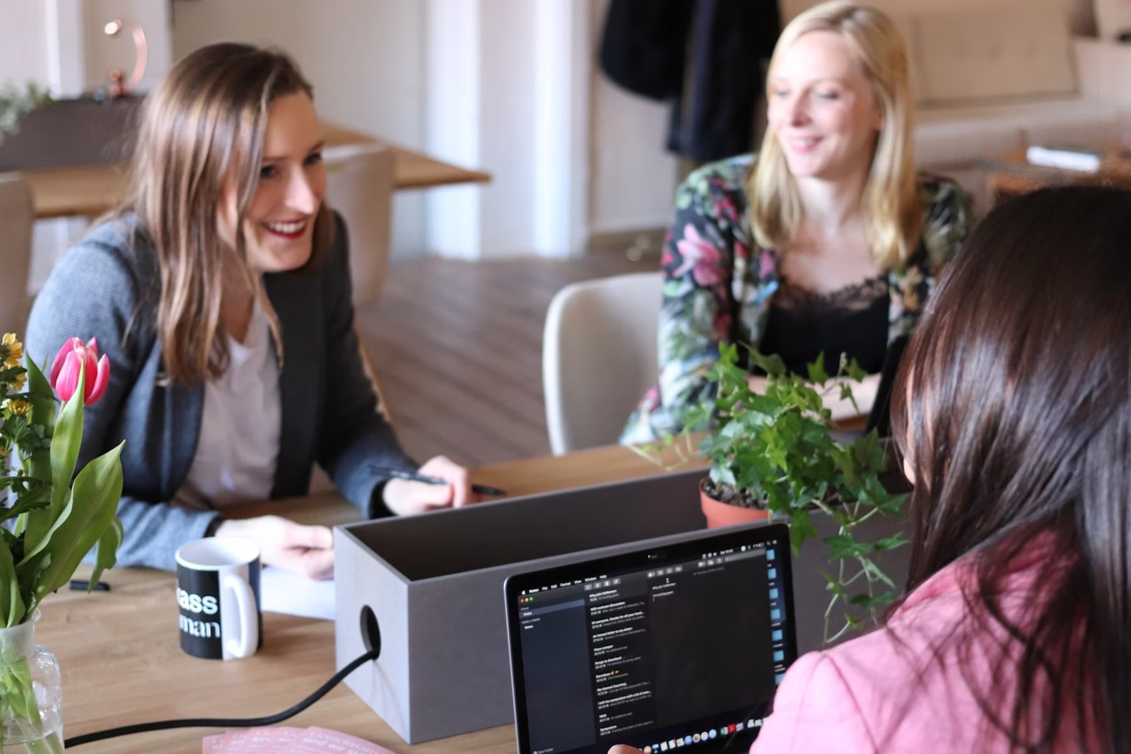 Three colleagues in an office meeting with laptop.